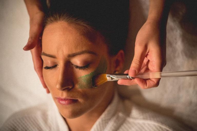 Woman getting a clay mask facial in a spa.